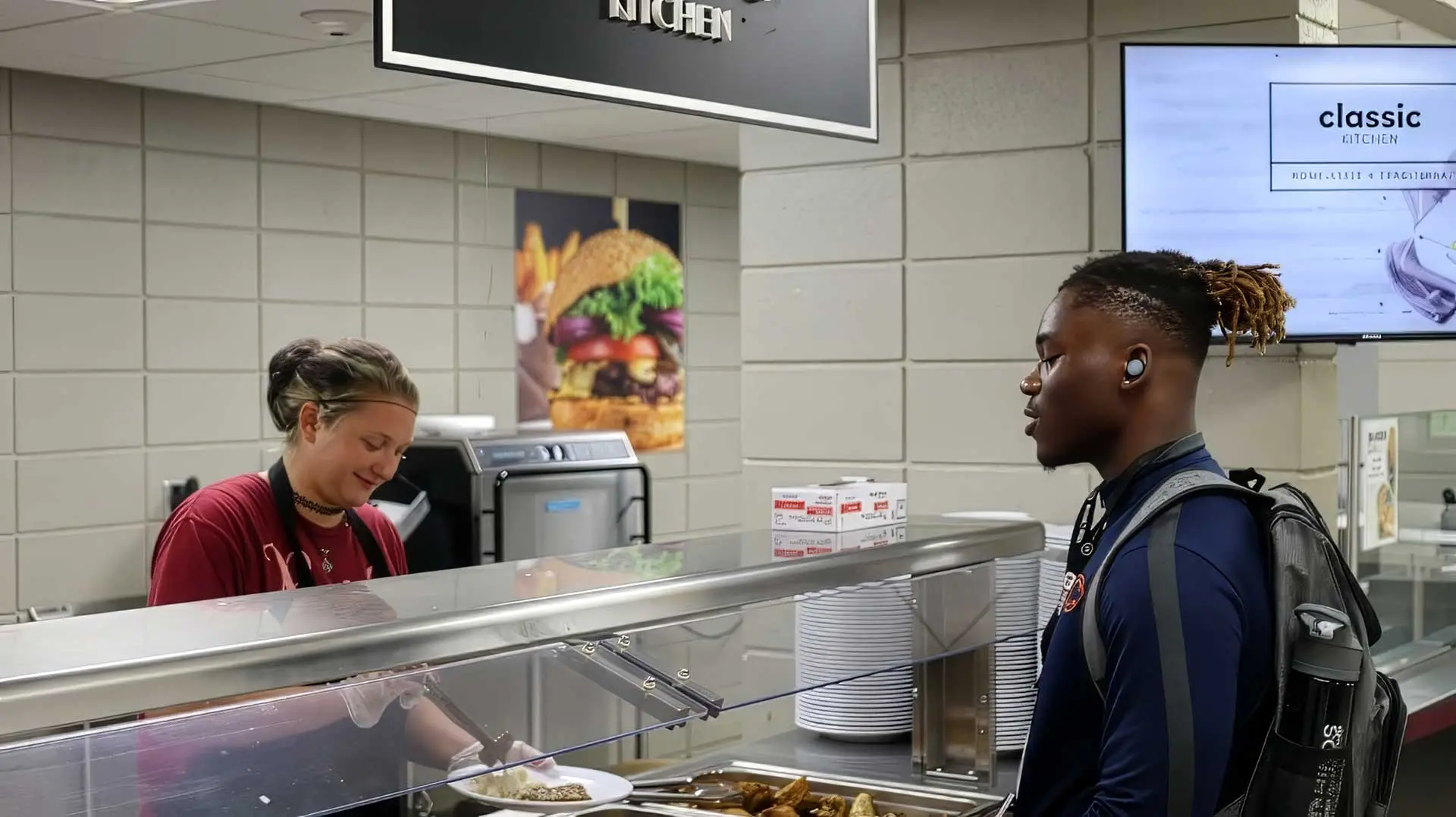 Student waiting for plate to be prepared by staff in serving line