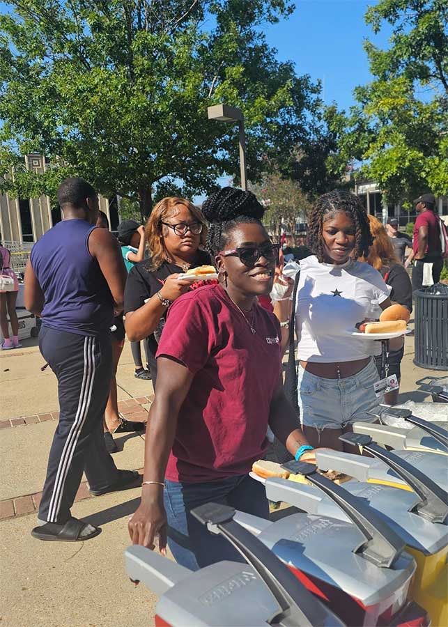 Patrons in line at condiment station outside in courtyard